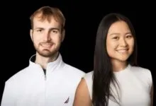 Portrait of a man and woman smiling against a black background.