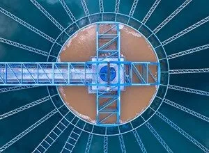 Aerial view of a circular water treatment plant with radial arms and a central structure.