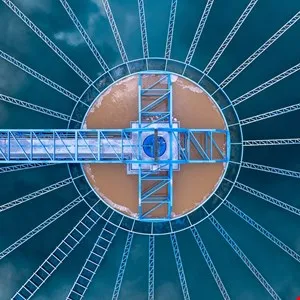 Aerial view of a circular water treatment plant with radial arms and a central structure.
