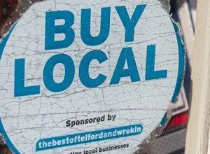 "Buy Local" sticker with blue text on a white background, promoting local businesses.