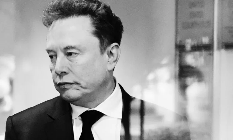 Black and white portrait of Elon Musk in a suit and tie.
