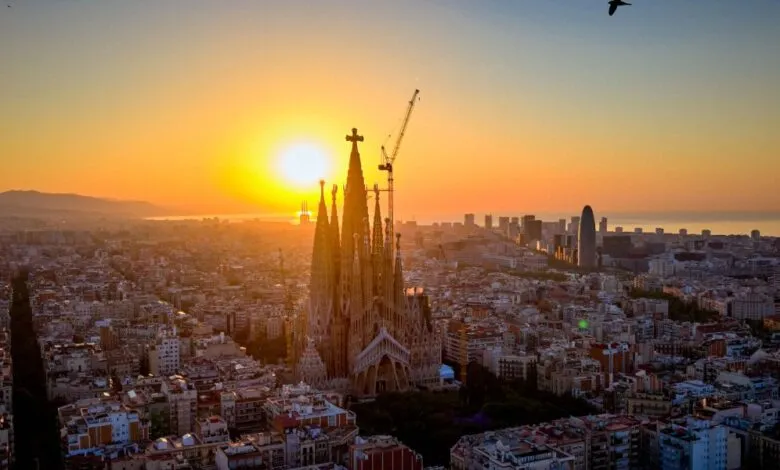 Sagrada Familia cathedral in Barcelona at sunrise, construction crane visible.