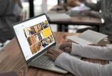 Person using Acer laptop with photo gallery open on a wooden table.