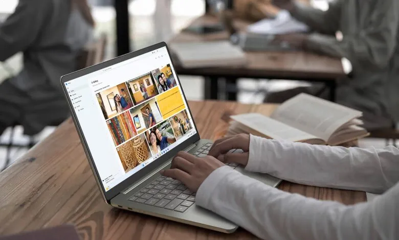 Person using Acer laptop with photo gallery open on a wooden table.