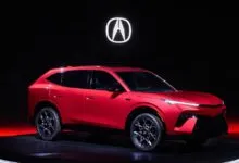 Red Acura SUV prototype on a rotating platform with the Acura logo in the background.