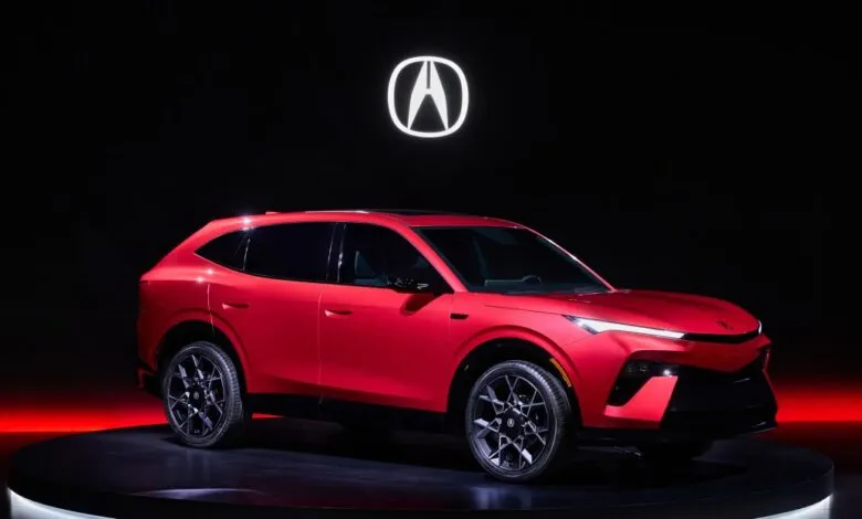 Red Acura SUV prototype on a rotating platform with the Acura logo in the background.