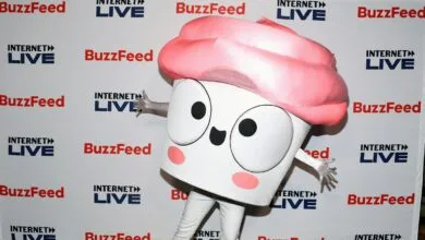 Cupcake mascot poses in front of BuzzFeed Internet Live backdrop.