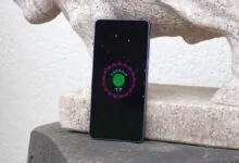 Smartphone displaying Android 17 logo against stone statue.