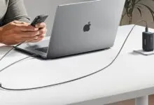 Anker 140W 2-in-1 USB-C cable charging phone and laptop on a white desk.
