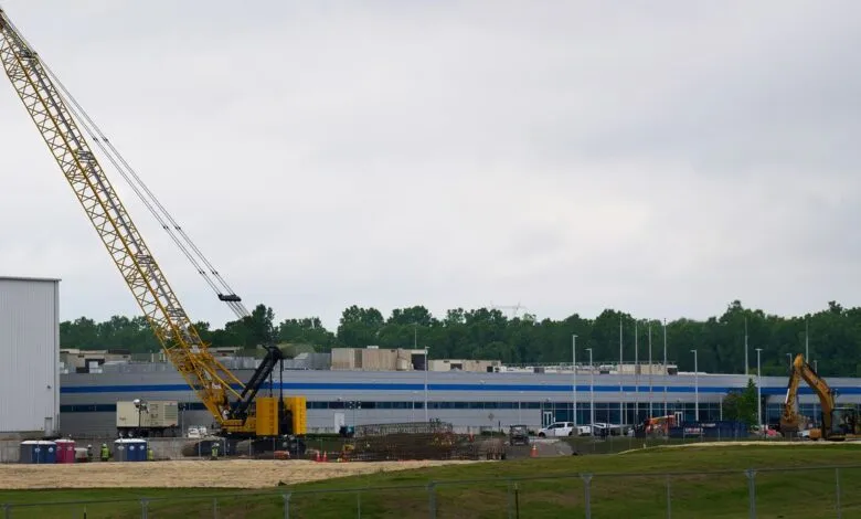 Construction site with a large yellow crane and building under construction.
