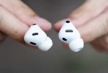 Close-up of two white Apple AirPods Pro held between fingers.