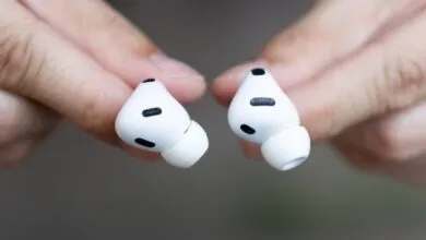 Close-up of two white Apple AirPods Pro held between fingers.