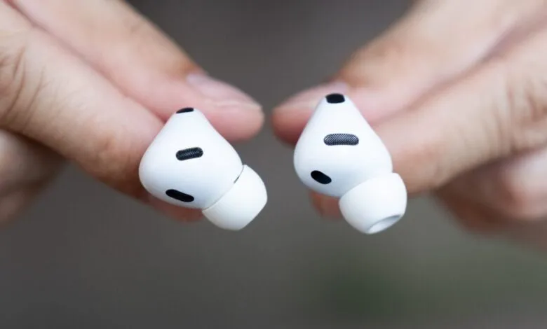 Close-up of two white Apple AirPods Pro held between fingers.