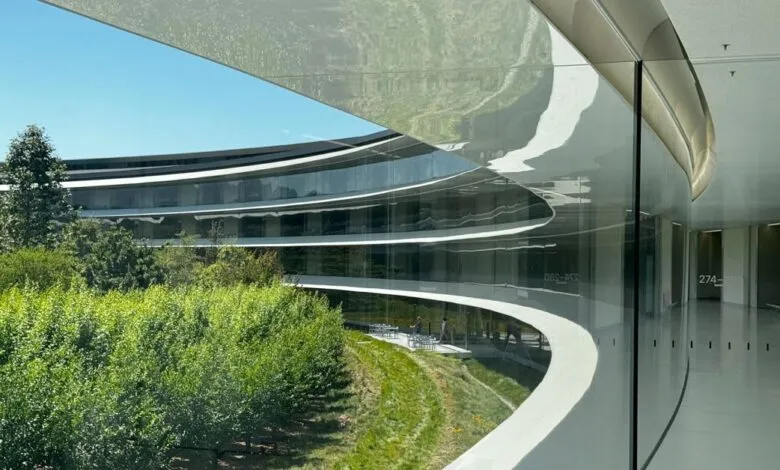 View of Apple Park through curved glass, showing exterior and interior spaces.