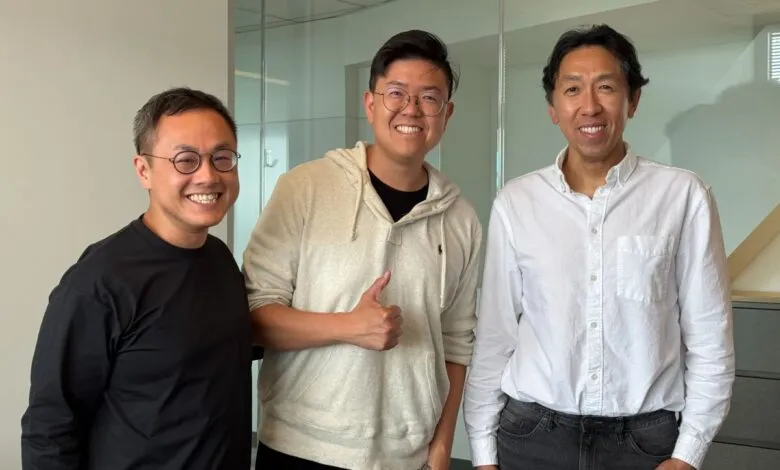 Three smiling men pose indoors against a neutral background.