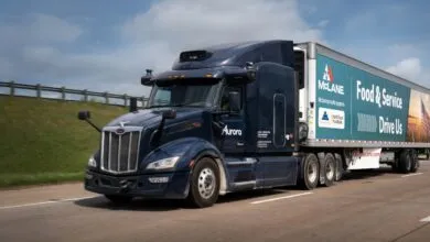Autonomous McLane semi-truck driving on highway, Aurora logo visible.