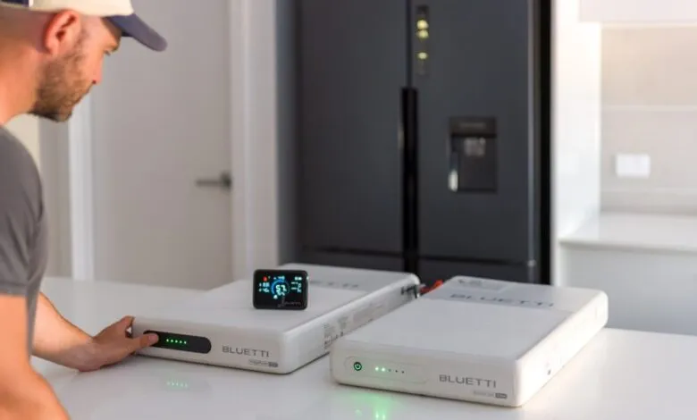 Man setting up BLUETTI power stations for home battery backup.