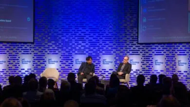 Two speakers on stage at MIT Technology Review event, audience present.