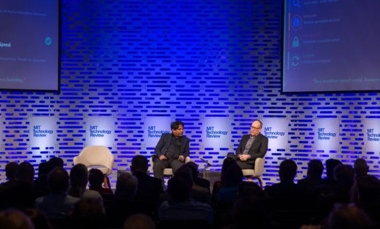 Two speakers on stage at MIT Technology Review event, audience present.