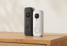 Two Blink 2K video doorbells, one black and one white, on a wooden surface.