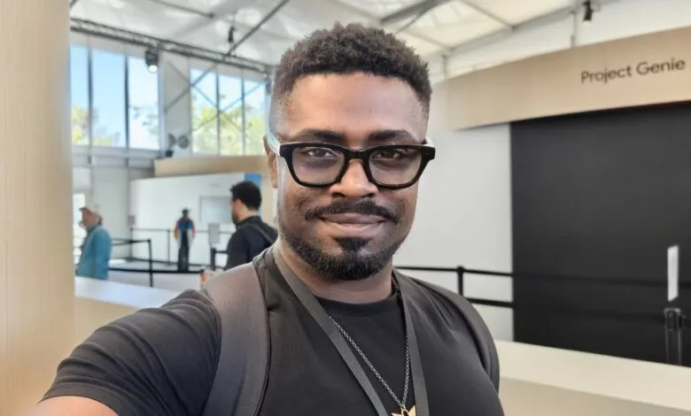 Smiling man with glasses takes a selfie at 'Project Genie' exhibit.