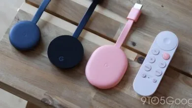 Three Google Chromecasts and a remote on a wooden surface.