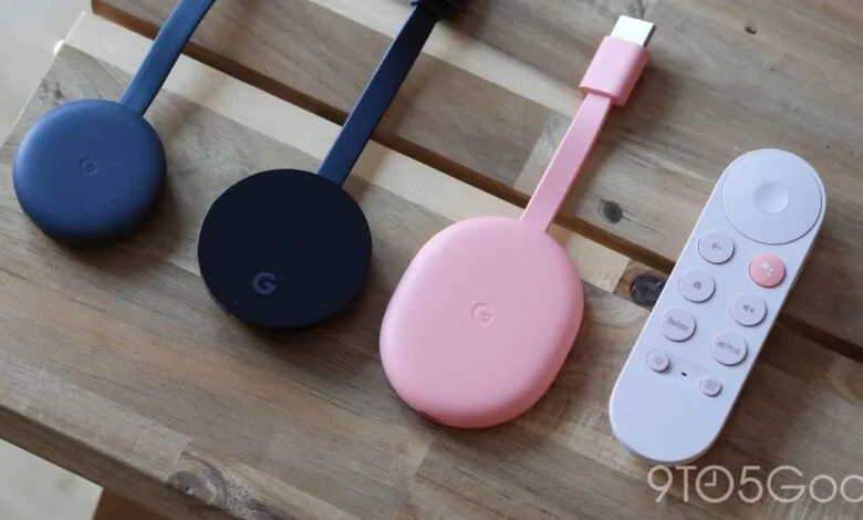 Three Google Chromecasts and a remote on a wooden surface.
