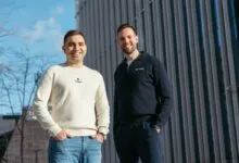 Two men smiling, wearing 'Ocean' branded sweaters, stand outdoors.