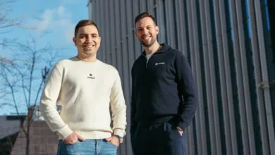 Two men smiling, wearing 'Ocean' branded sweaters, stand outdoors.