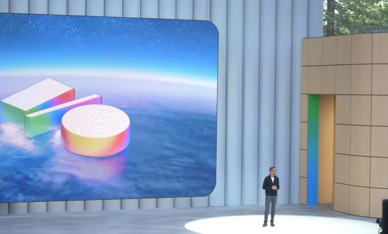 Sundar Pichai presents on stage with colorful geometric shapes on screen.