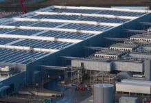 Large data center with solar panels on roof and cooling systems.