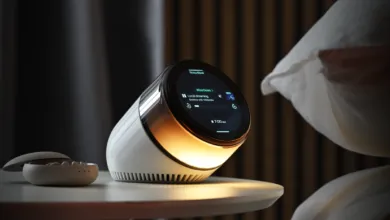 Smart sleep device on nightstand with earbuds and pillow nearby.