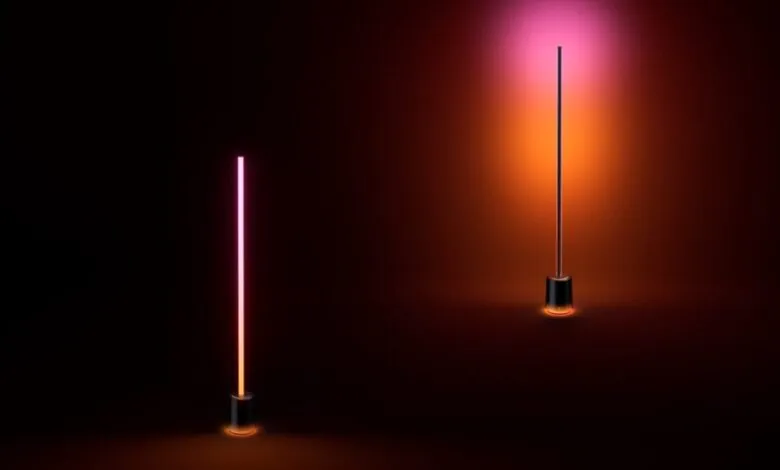 Two modern floor lamps with gradient pink and orange lighting in a dark room.