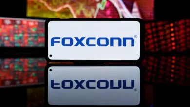 Foxconn logo displayed on a smartphone screen with stock market data in background.