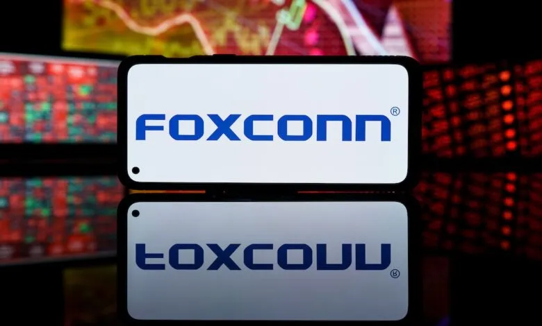 Foxconn logo displayed on a smartphone screen with stock market data in background.