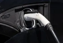 Electric car charging: white plug inserted into black vehicle port.