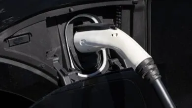 Electric car charging: white plug inserted into black vehicle port.