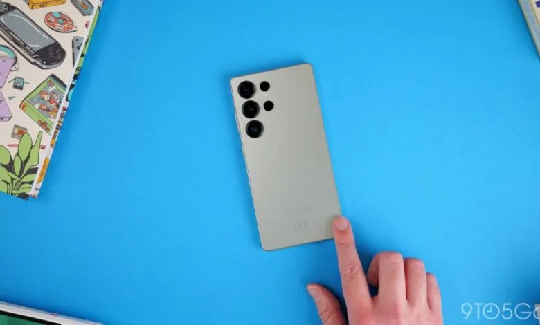 Samsung Galaxy S23 Ultra on blue background with hand touching the screen.