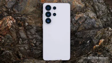 White smartphone with camera lenses on a textured rock surface.