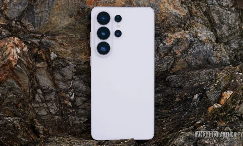White smartphone with camera lenses on a textured rock surface.