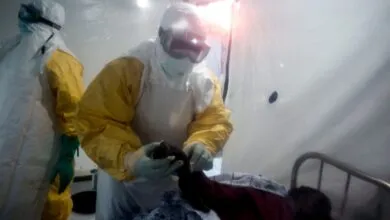 Medical workers in protective gear attend to patient in isolation unit.