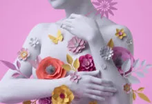 White female bust covered in colorful paper flowers on pink background.