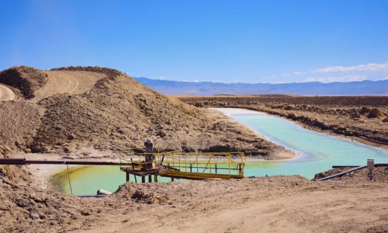 Lithium mining brine pools with yellow platform and pipes under a clear blue sky.
