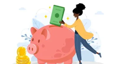 Woman putting money into a pink piggy bank with gold coins nearby.
