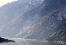 Alaskan fjord with steep mountains and ice floes in the water.