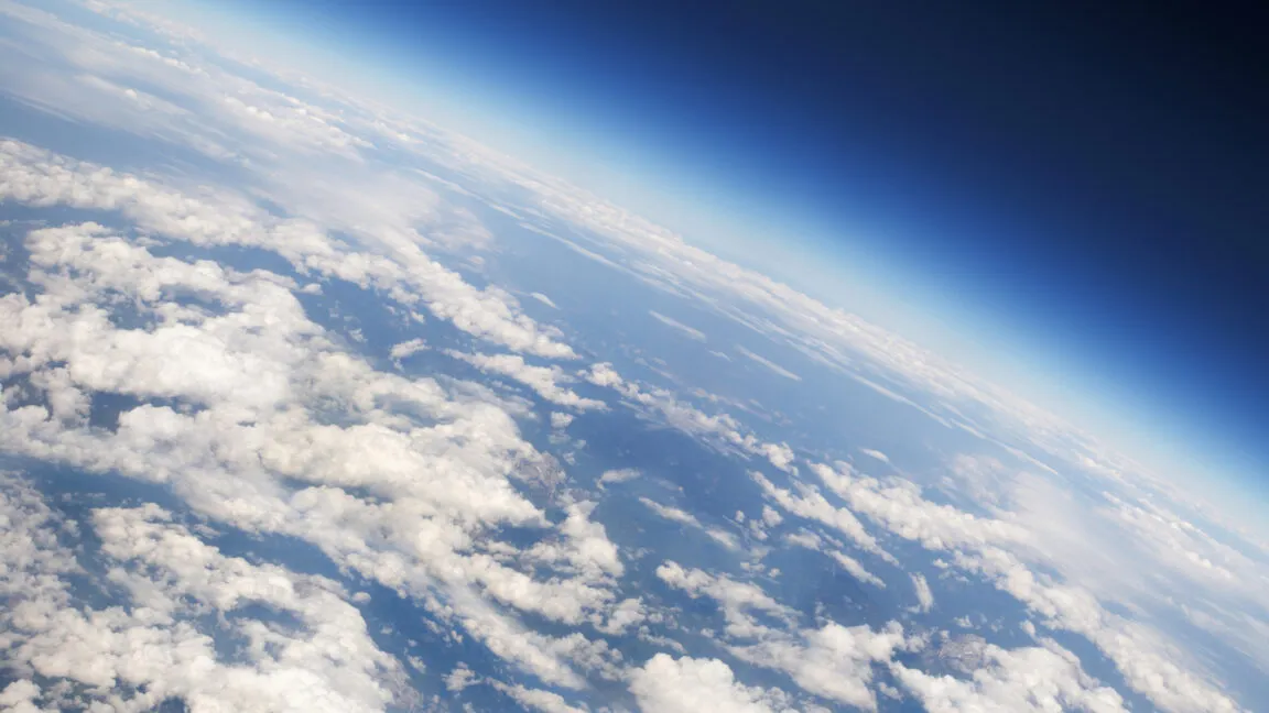 Aerial view of Earth's horizon with clouds and blue atmosphere.