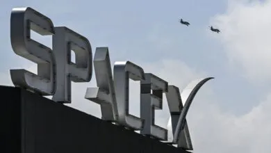 SpaceX sign with two jets flying in the sky above.