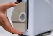 Hand inserting CD into a light gray computer tower.