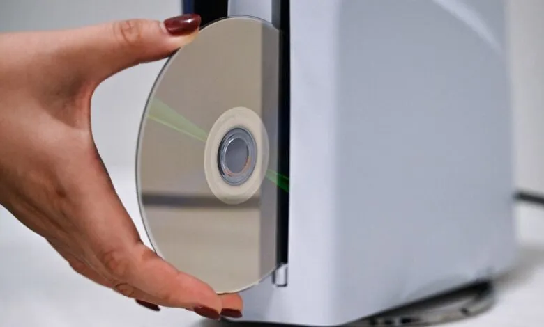 Hand inserting CD into a light gray computer tower.