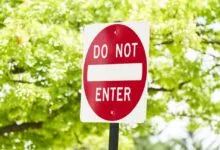 Red and white 'Do Not Enter' sign against green foliage.